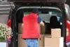 Person packt Kartons als Einladehilfe in ein Auto